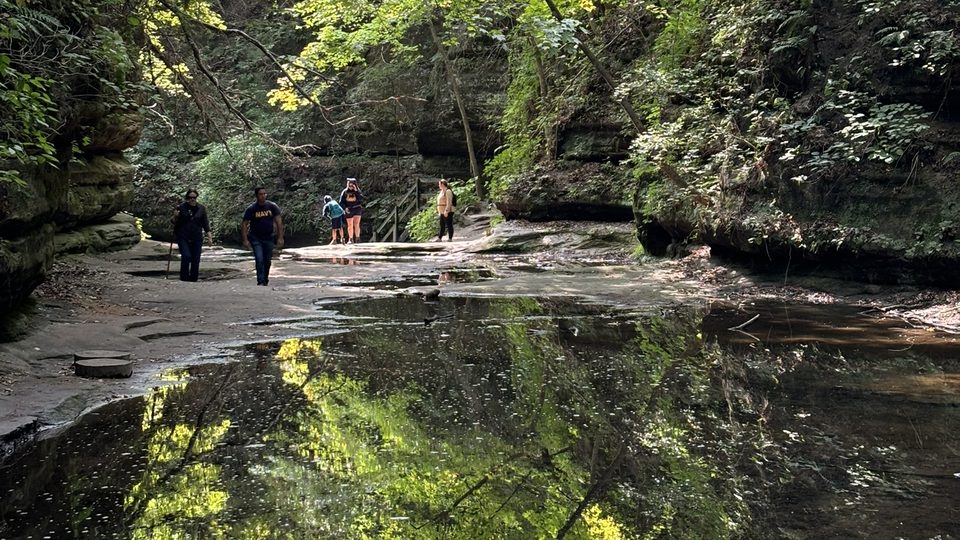 Pack families walking a canyon trail beside still water at Starved Rock